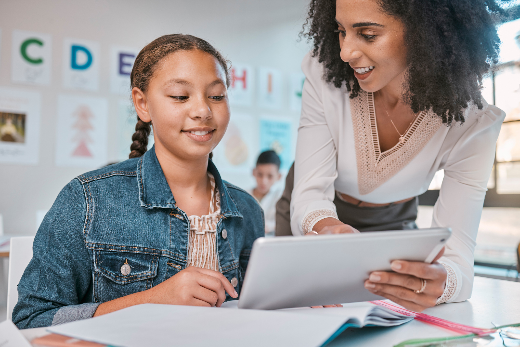 Female teacher and student on tablet reviewing a presentation idea