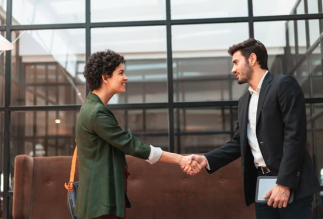 An MBA graduate shakes hands with a business professional at a job interview