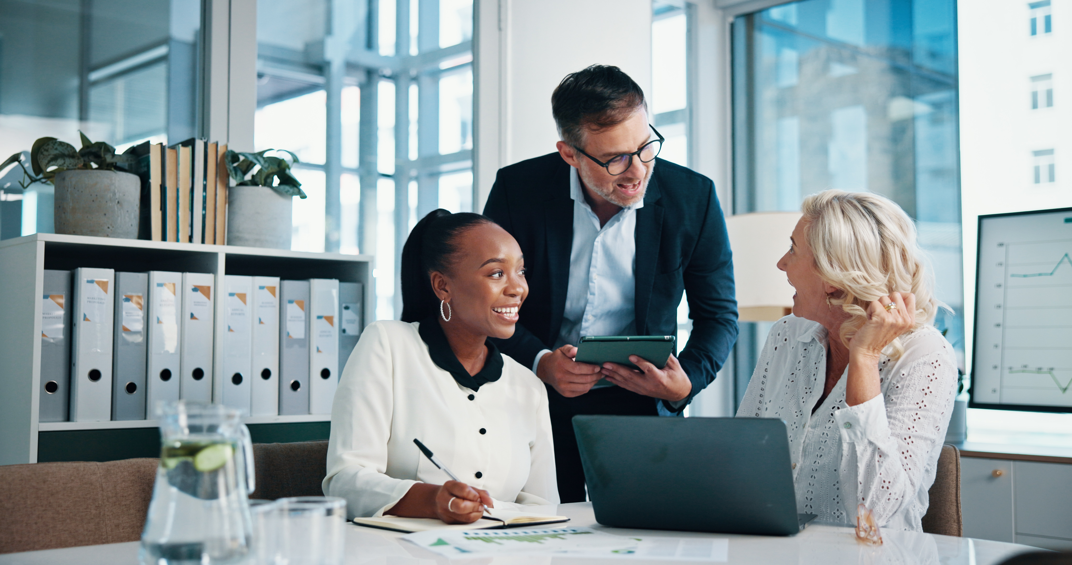 An mba graduate takes notes during a small team meeting.